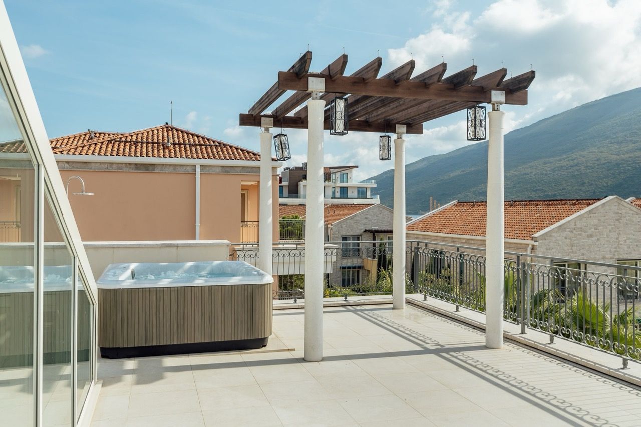 Terrace with a jacuzzi and wooden pergola at a villa in Portonovi, Kumbor, Montenegro, with mountain and sea views.