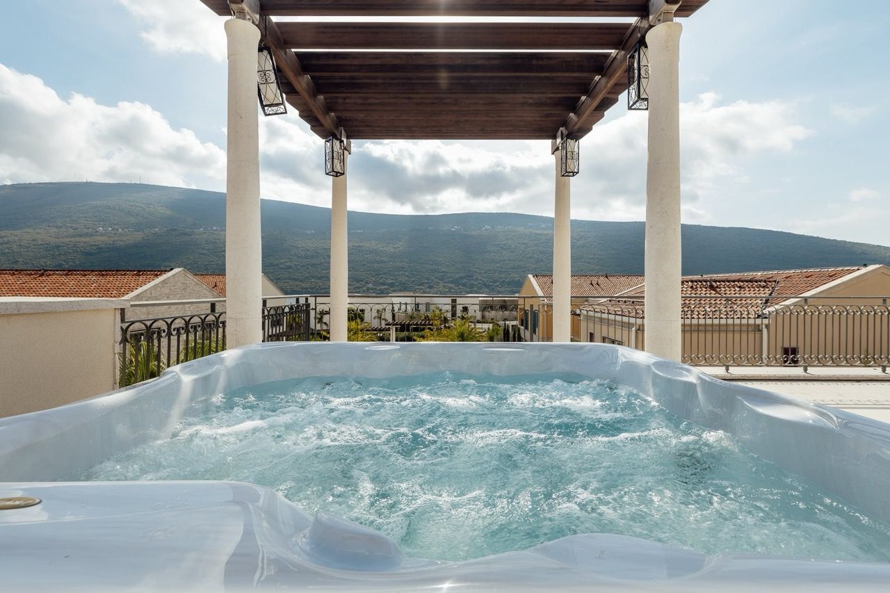 Jacuzzi on the terrace of a villa in Portonovi, Kumbor, Montenegro, with mountain views and Mediterranean architecture.