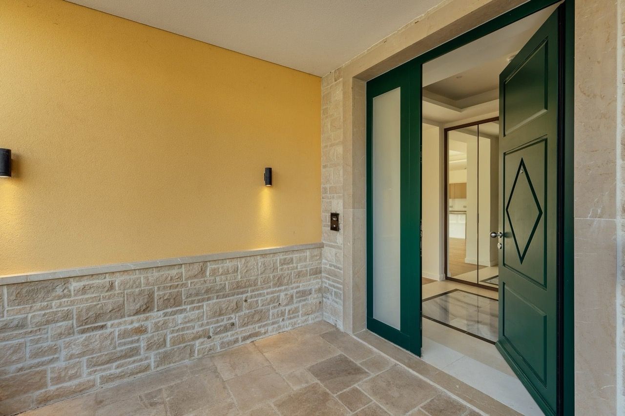Entrance to the Portonovi villa in Kumbor, Montenegro: green door, stone facade finish, and stylish lighting.