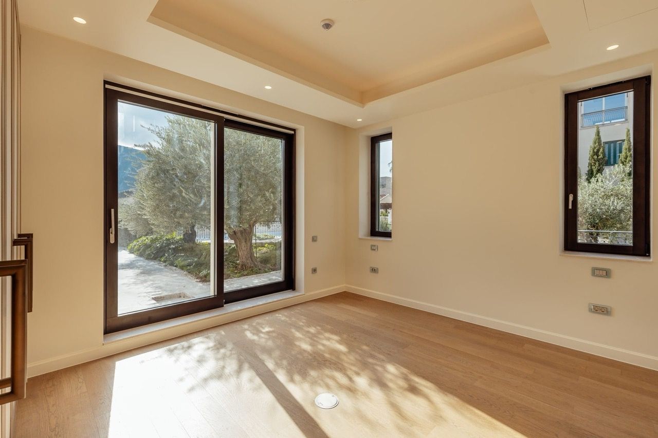 Bright living room with panoramic windows and a view of the garden in the Portonovi villa, Kumbor, Montenegro. Parquet flooring and modern design.