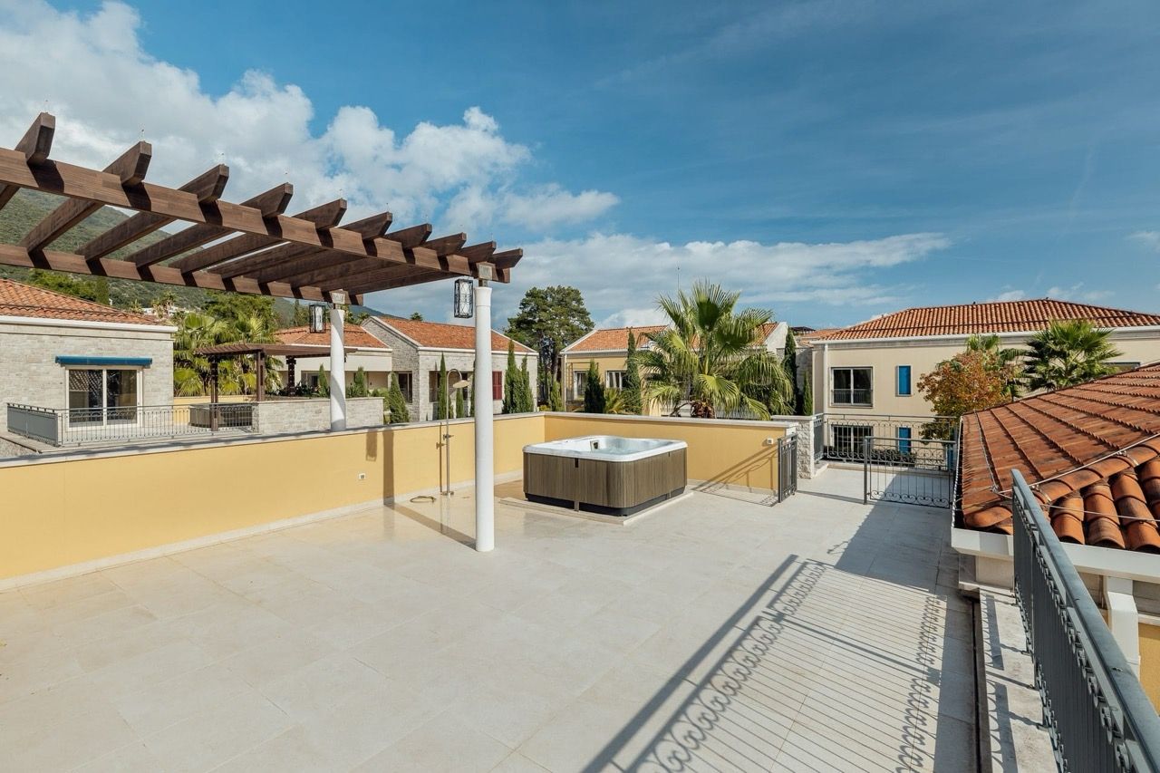 Villa terrace in Portonovi, Kumbor, Montenegro: an open area with a jacuzzi, wooden pergola, and a view of the complex.