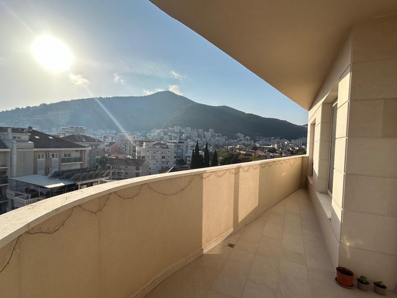 Prostran balkon s panoramskim pogledom na planine i grad Budvu, Crna Gora, u modernom stanu sa završnom obradom od pločica.