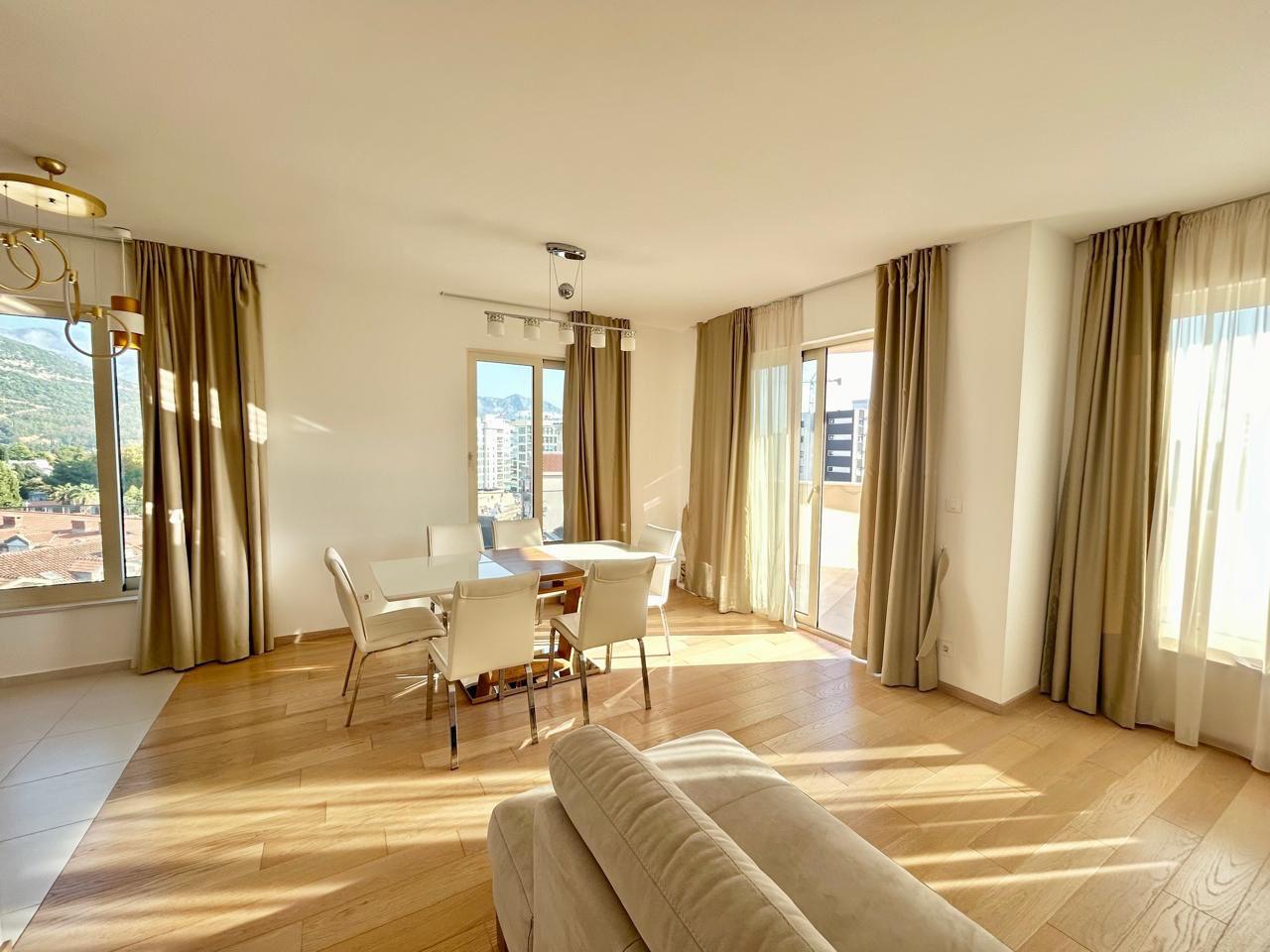 Svetla dnevna soba sa trpezarijskim delom i panoramskim prozorima u stanu u Budvi, Crna Gora. Moderan enterijer.