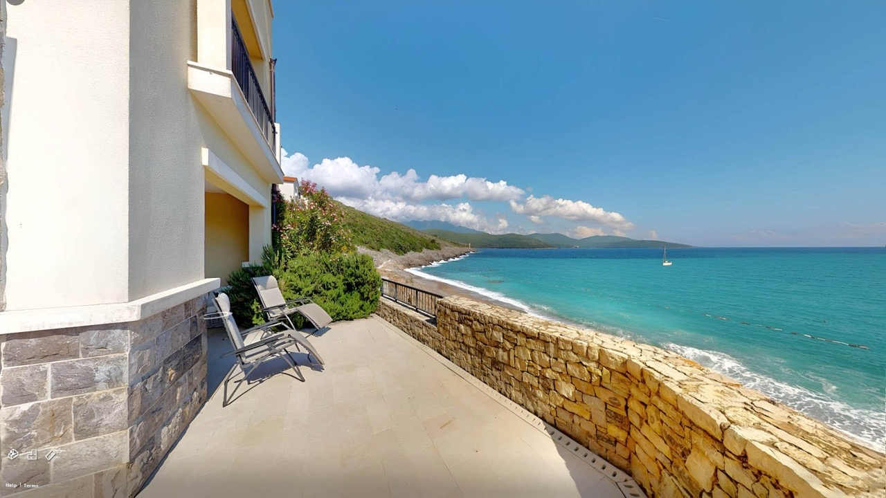 Terrasse mit Liegestühlen und Meerblick in den Apartments von Luštica Bay, Radovići, Montenegro. Steinverkleidung der Fassade.