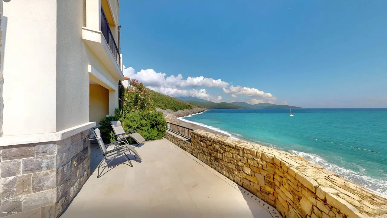 Terasa sa ležaljkama i pogledom na more u apartmanima Luštica Bay, Radovići, Crna Gora. Kamena fasadna obloga.