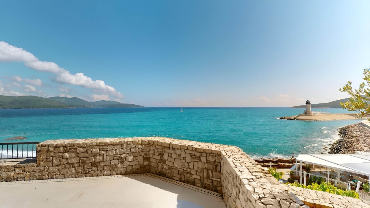 Blick von der Terrasse auf das Meer und den Leuchtturm in Luštica Bay, Radovići, Montenegro: Steinverkleidung und panoramischer Meerblick.