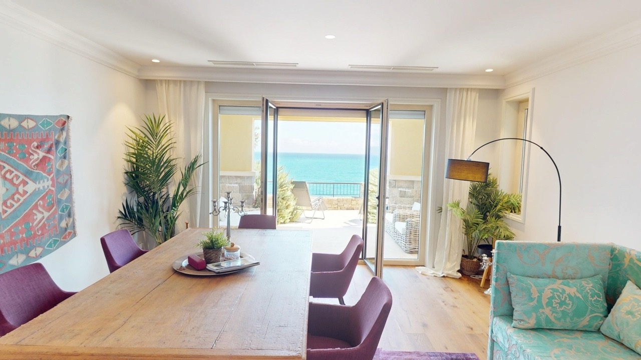 Wohnzimmer mit Meerblick in der Wohnung Luštica Bay, Radovići, Montenegro: Esstisch, violette Sessel und Terrasse.