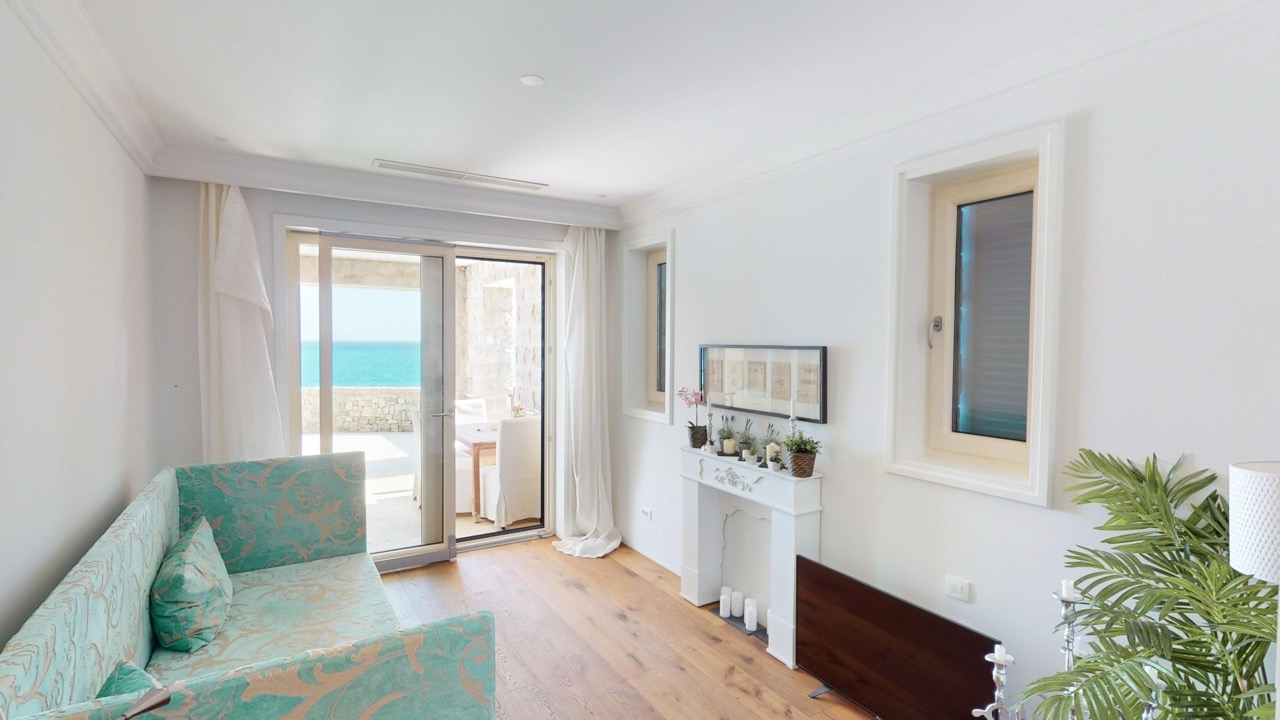 Helles Wohnzimmer mit Meerblick in der Wohnung Luštica Bay, Radovići, Montenegro: Sofa, Kamin und Terrasse.