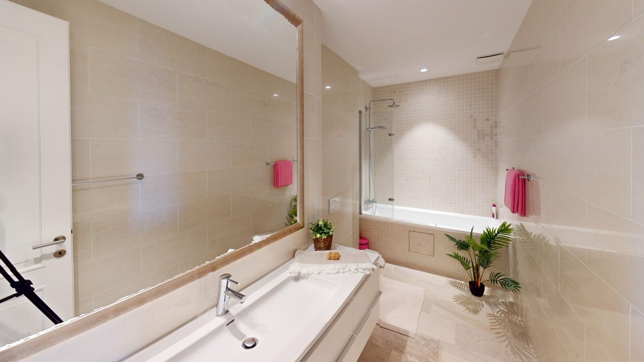 Modernes Badezimmer in einer Wohnung in Luštica Bay, Radovići, Montenegro: beige Fliesen, Badewanne und großer Spiegel.