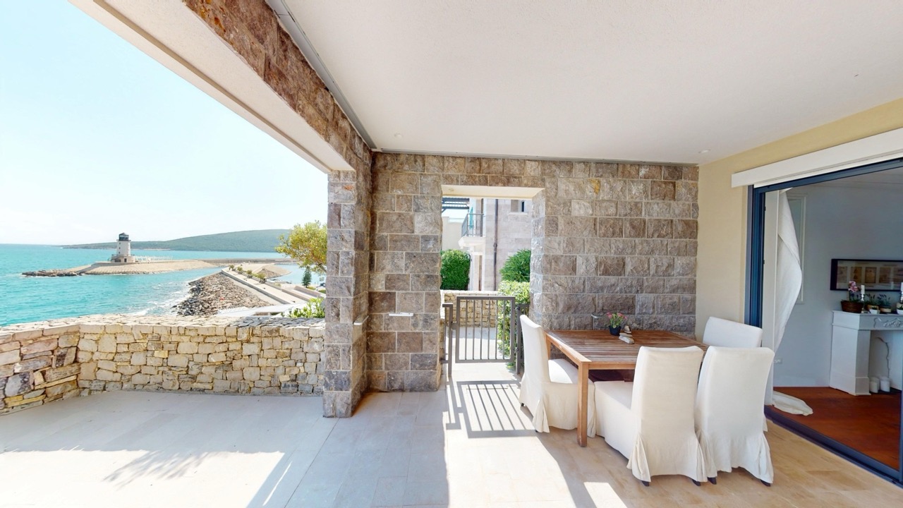 Terrasse mit Steinverkleidung und Essbereich in der Wohnung in Luštica Bay, Radovići, Montenegro, mit Meer- und Leuchtturmblick.