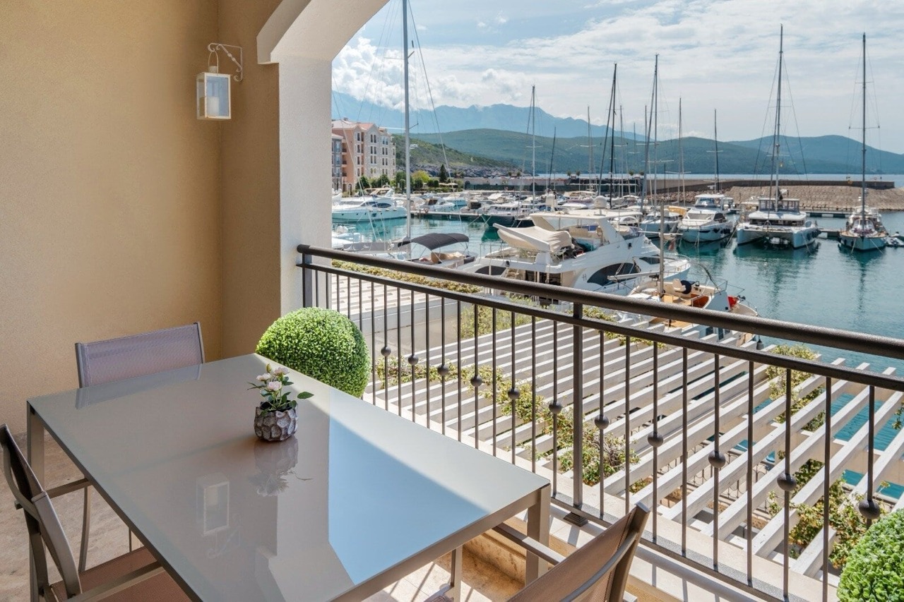 Balkon mit Essbereich und Blick auf den Yachthafen in Luštica Bay, Radovići, Montenegro.