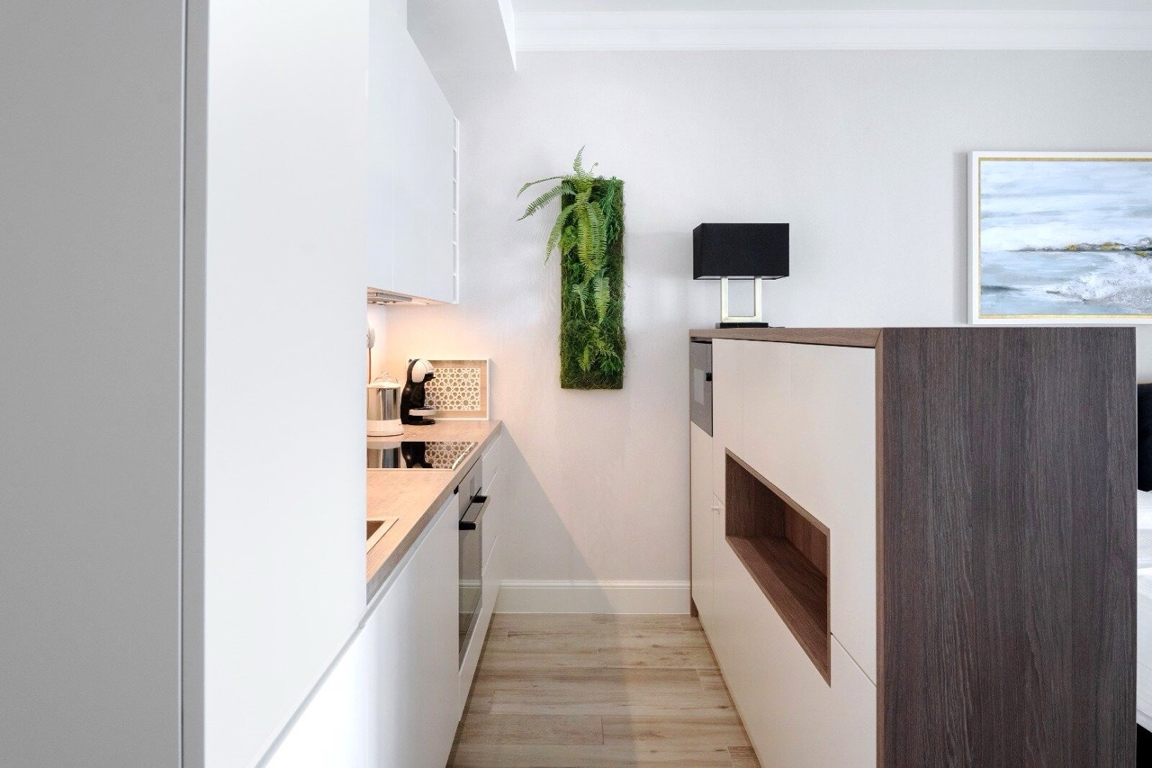 Moderne Küche in der Wohnung in Luštica Bay, Radovići, Montenegro: weiße Fronten, Holzarbeitsplatte und Moosdekor.