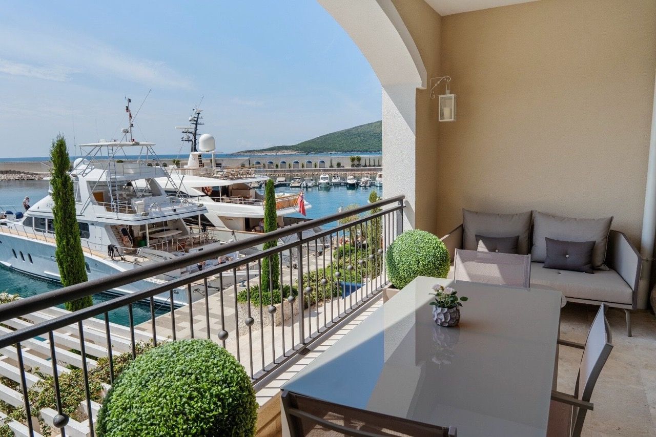 Balkon mit Möbeln und Blick auf die Marina und Yachten in Luštica Bay, Radovići, Montenegro. Exklusive Immobilie am Meer.