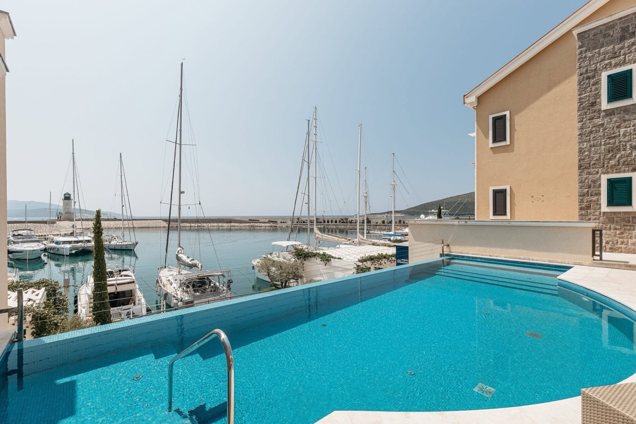 Infinity-Pool mit Blick auf den Yachthafen und die Yachten in der exklusiven Anlage Luštica Bay, Radovići, Montenegro.