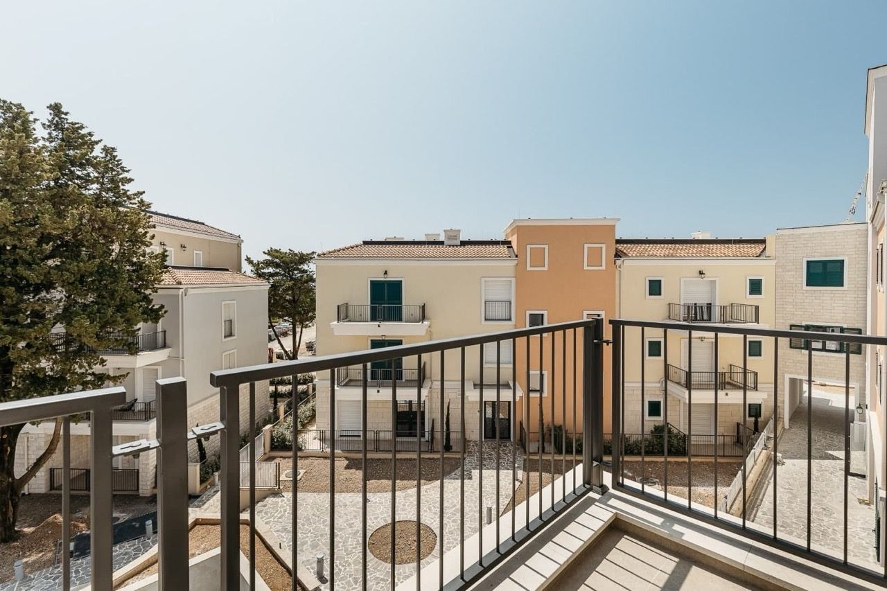 Vue depuis le balcon sur un complexe résidentiel moderne à Luštica Bay, Radovići, Monténégro : façades claires et terrain bien entretenu.