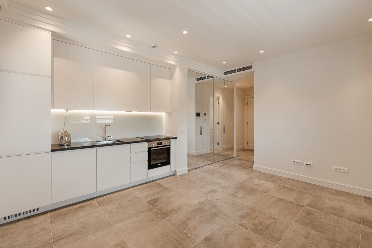 Cuisine moderne dans l’appartement de Luštica Bay, Radovići, Monténégro : façades blanches, électroménager intégré et armoire miroir.
