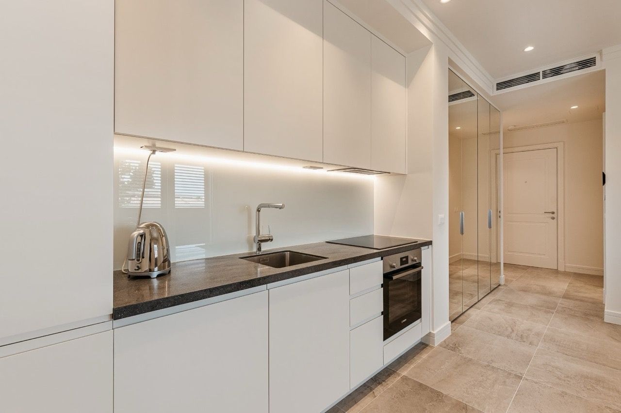 Cuisine blanche moderne avec plan de travail foncé dans un appartement du complexe Luštica Bay, Radovići, Monténégro.