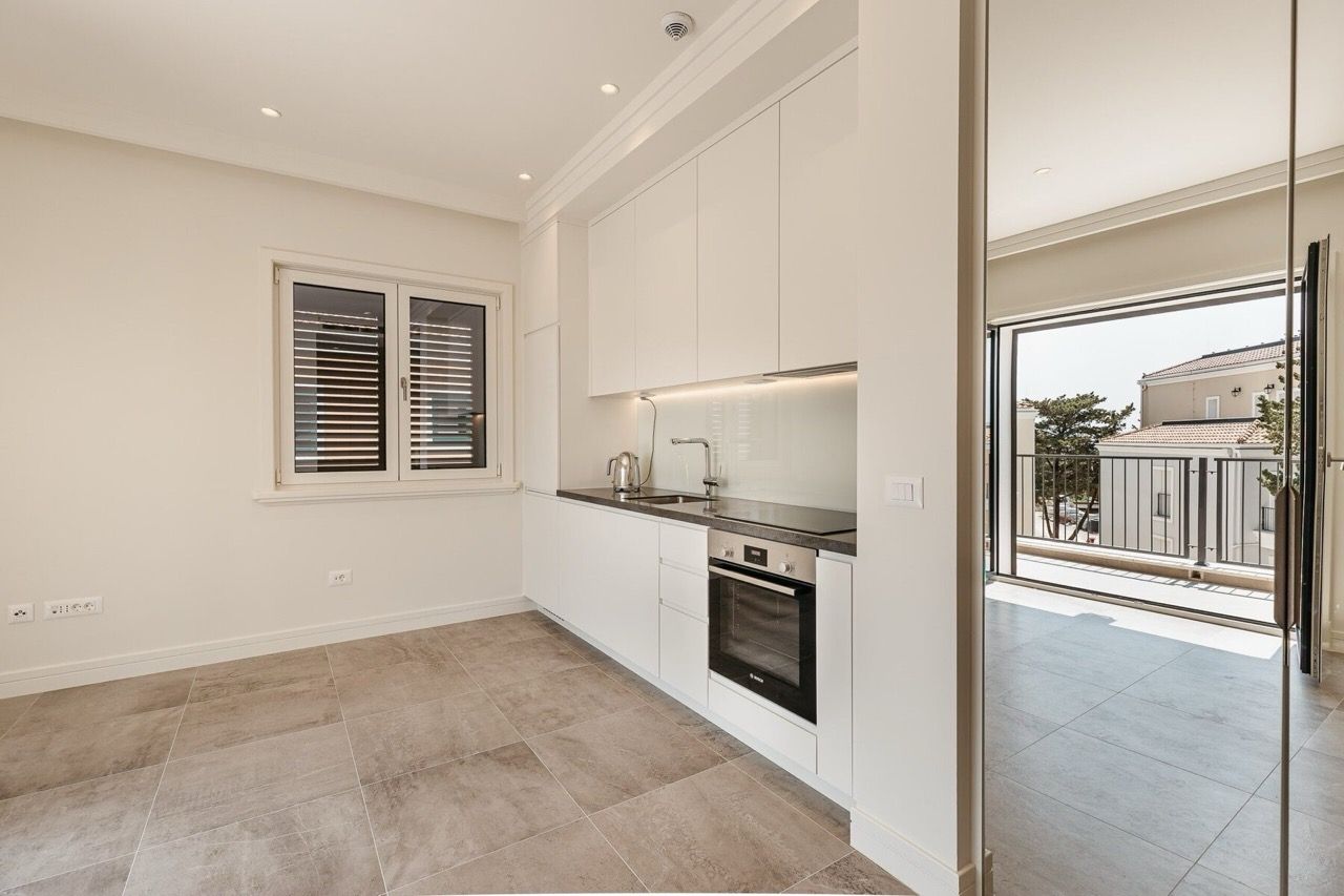 Cuisine moderne avec mobilier blanc dans l’appartement du complexe Lustica Bay, Radovici, Monténégro, accès à la terrasse.