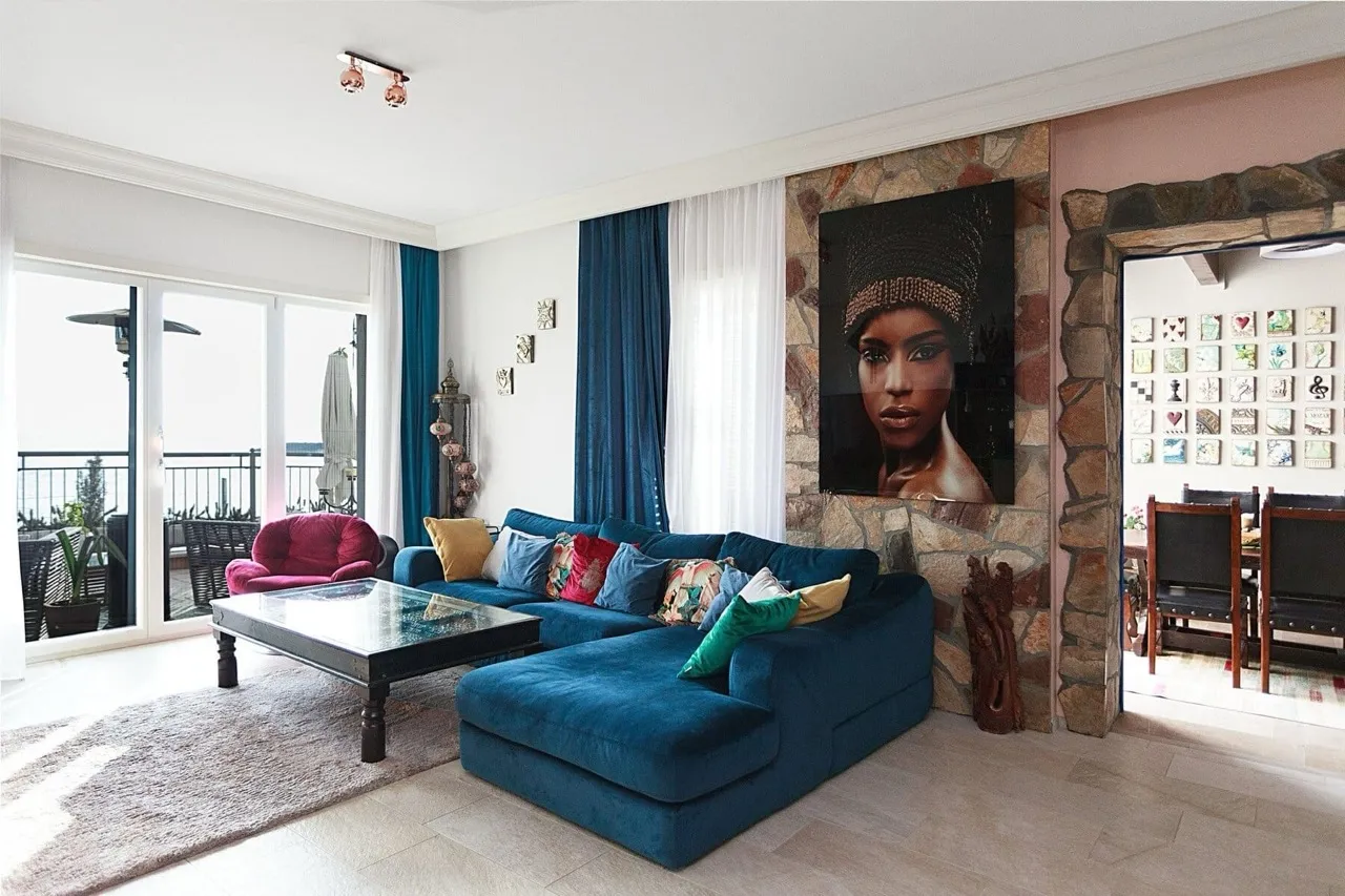 Wohnzimmer mit blauem Sofa und Steinwand in einer Villa in Luštica Bay, Radovići, Montenegro, mit Zugang zur Terrasse.