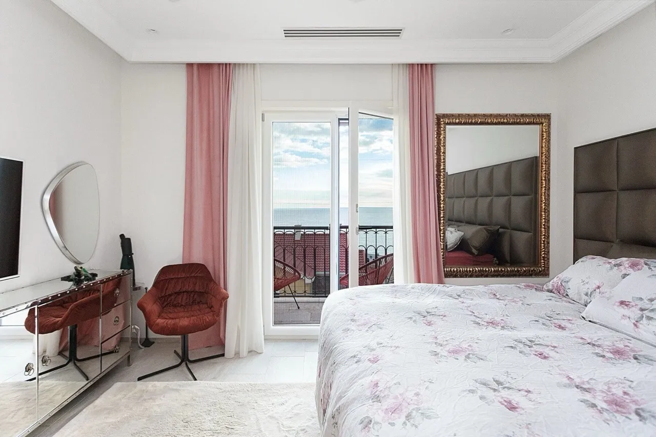 Schlafzimmer mit Meerblick in einer Villa in Luštica Bay, Radovići, Montenegro: Doppelbett, Spiegel und Terrasse.