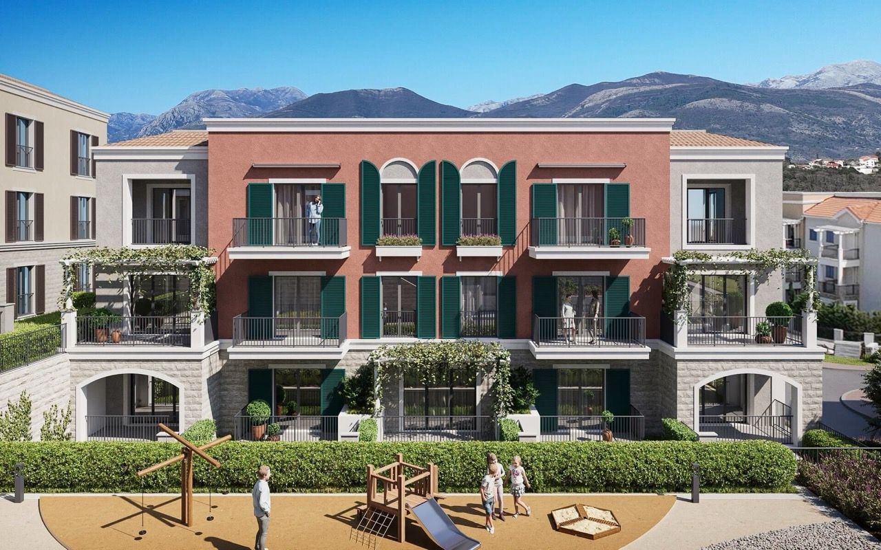 Façade du complexe résidentiel à Luštica Bay, Radovići, Monténégro : terrasses avec volets verts et aire de jeux pour enfants près de l’immeuble.