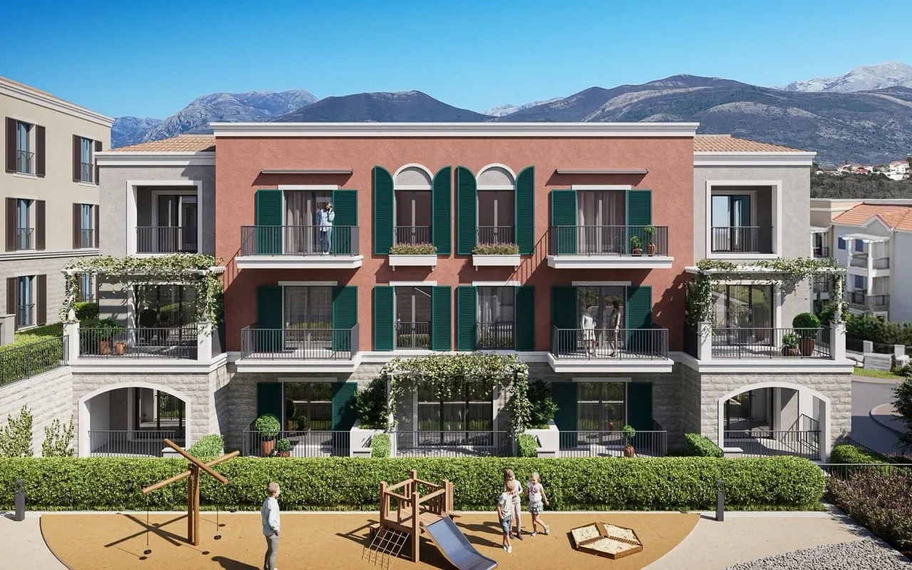 Fassade des Wohnkomplexes in Luštica Bay, Radovići, Montenegro: Terrassen mit grünen Fensterläden und ein Spielplatz am Haus.
