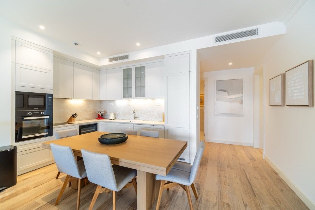 Cuisine moderne dans l’appartement de Luštica Bay, Radovići, Monténégro : meubles clairs, table en bois et appareils électroménagers intégrés.