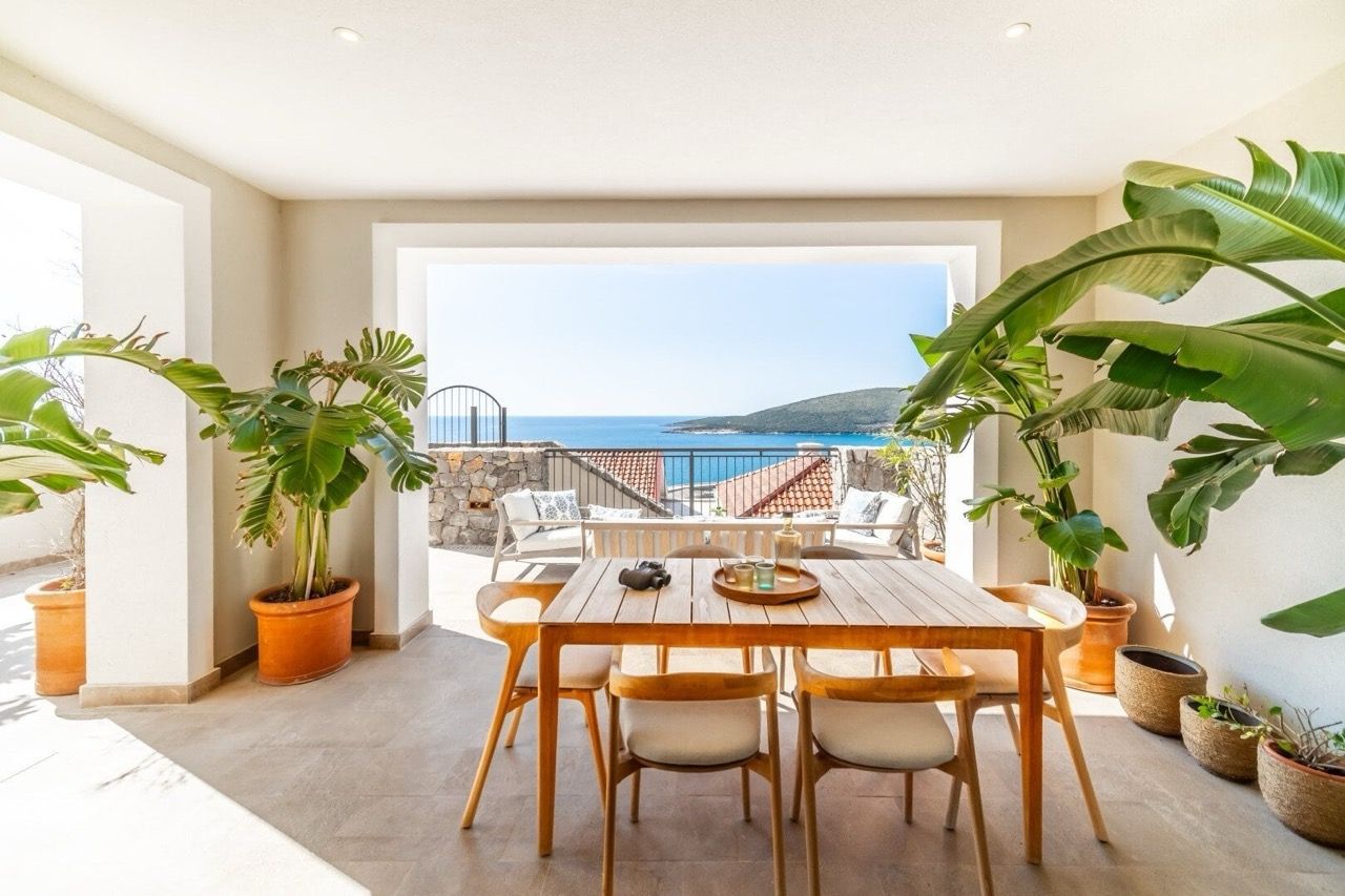 Terrasse avec coin repas et vue sur la mer dans l’appartement Luštica Bay, Radovići, Monténégro : table en bois et plantes.
