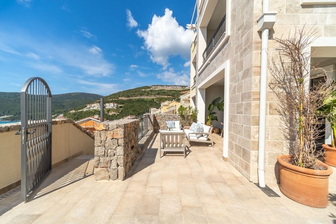 Spacieuse terrasse avec mobilier de jardin dans un appartement à Luštica Bay, Radovići, Monténégro, vue sur les montagnes et la mer.