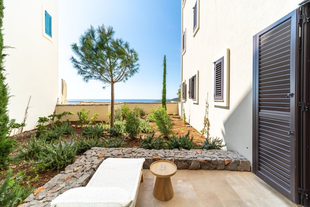 Terrasse avec vue sur la mer dans les appartements Luštica Bay, Radovići, Monténégro : transat, jardin et finition en pierre.