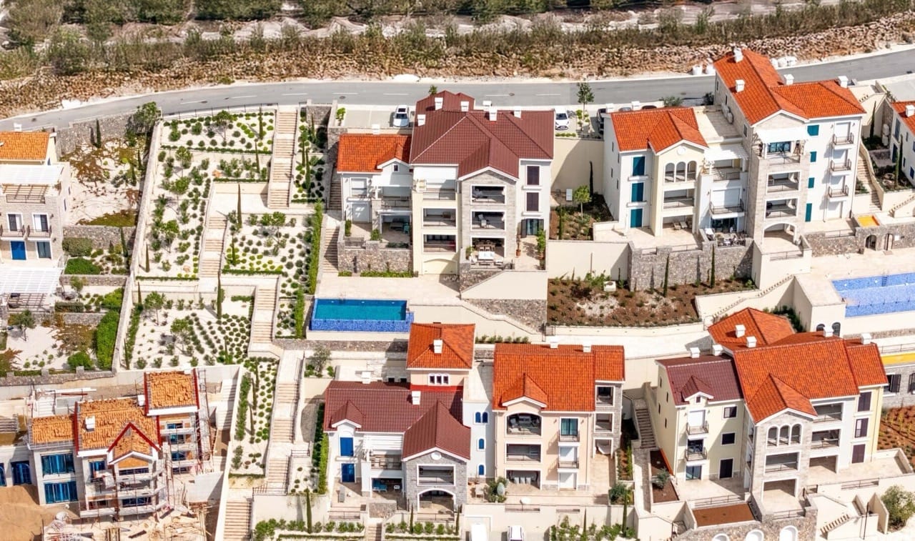 Vue aérienne du complexe résidentiel Lustica Bay à Radovici, Monténégro : villas aux toits rouges, avec terrasses et piscines.