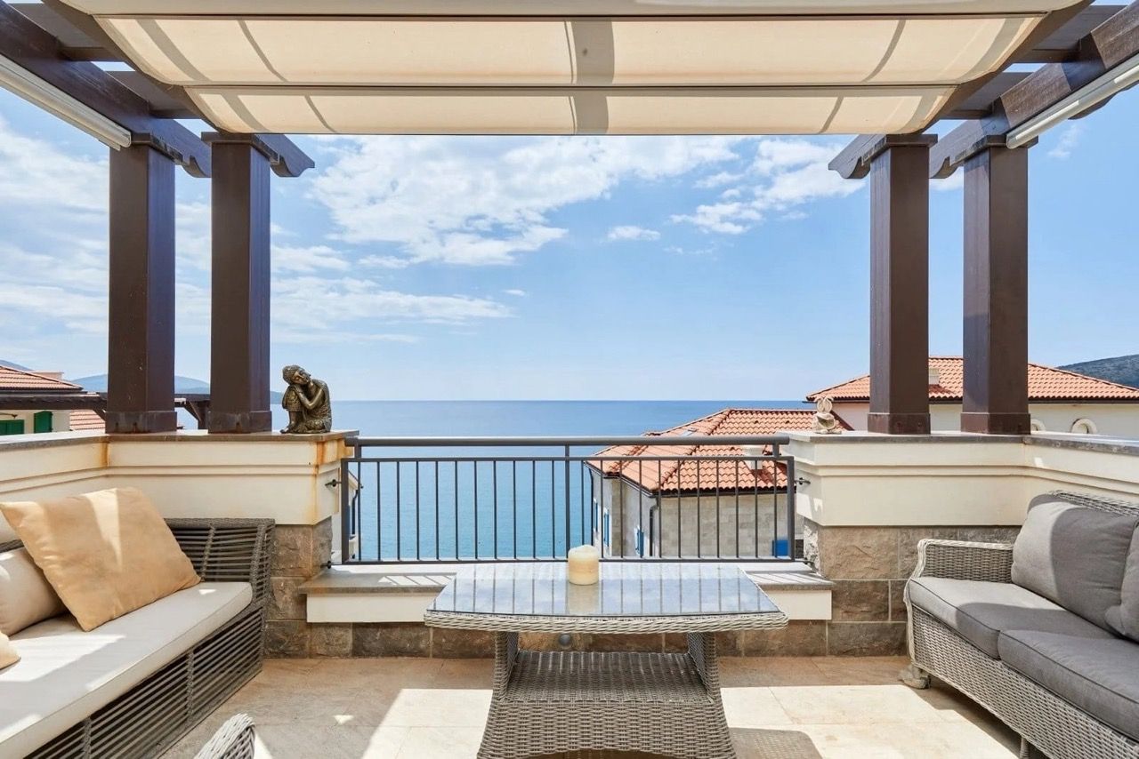 Terrasse avec mobilier en osier et vue sur la mer dans l’appartement Lustica Bay, Radovici, Monténégro.