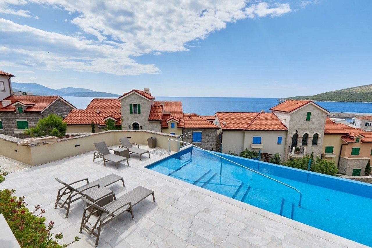 Piscine à débordement avec chaises longues et vue panoramique sur la mer à Luštica Bay, Radovići, Monténégro.
