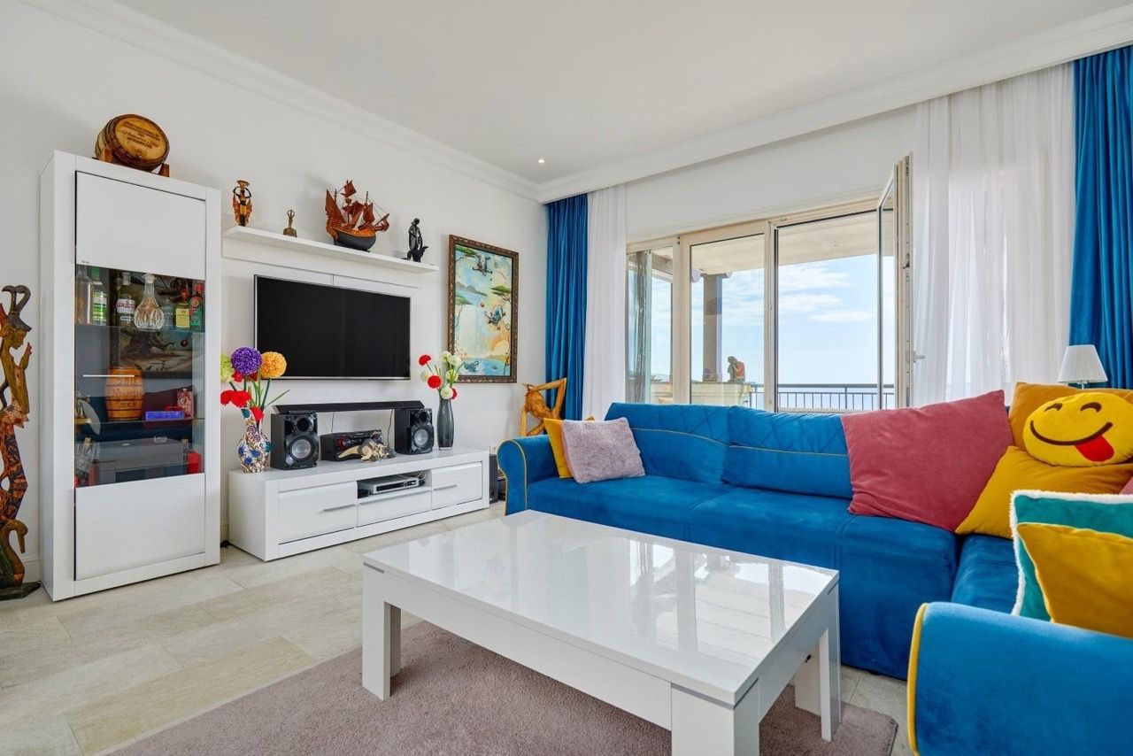 Salon lumineux avec canapé bleu et vue sur la mer dans un appartement à Luštica Bay, Radovići, Monténégro.