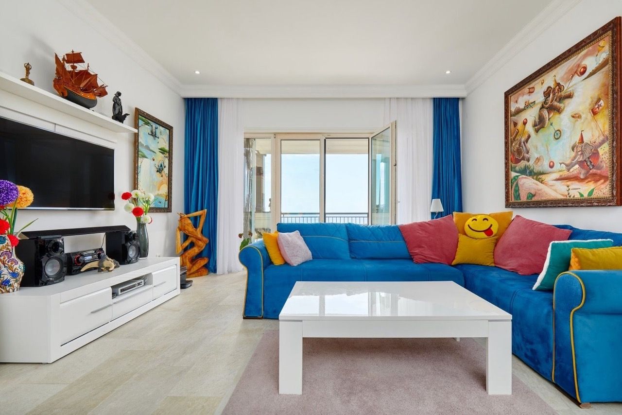 Salon lumineux avec canapé bleu et vue sur la mer dans l’appartement de Luštica Bay, Radovići, Monténégro.
