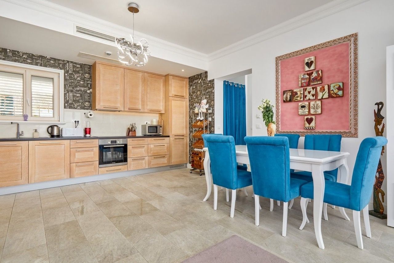 Cuisine-salle à manger avec mobilier en bois et chaises bleues dans l’appartement Luštica Bay, Radovići, Monténégro.