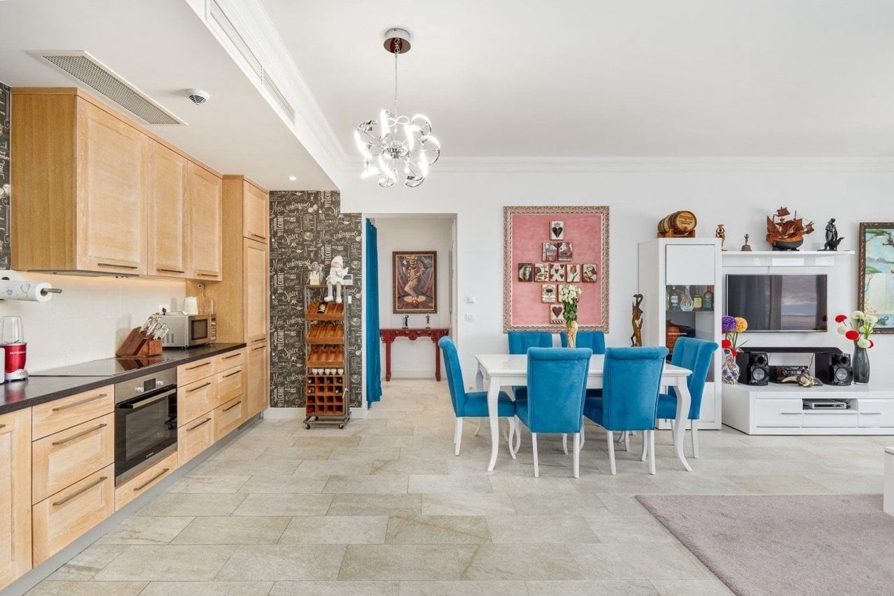 Salon avec cuisine dans l’appartement Luštica Bay, Radovići, Monténégro : mobilier clair, chaises bleues et intérieur élégant.