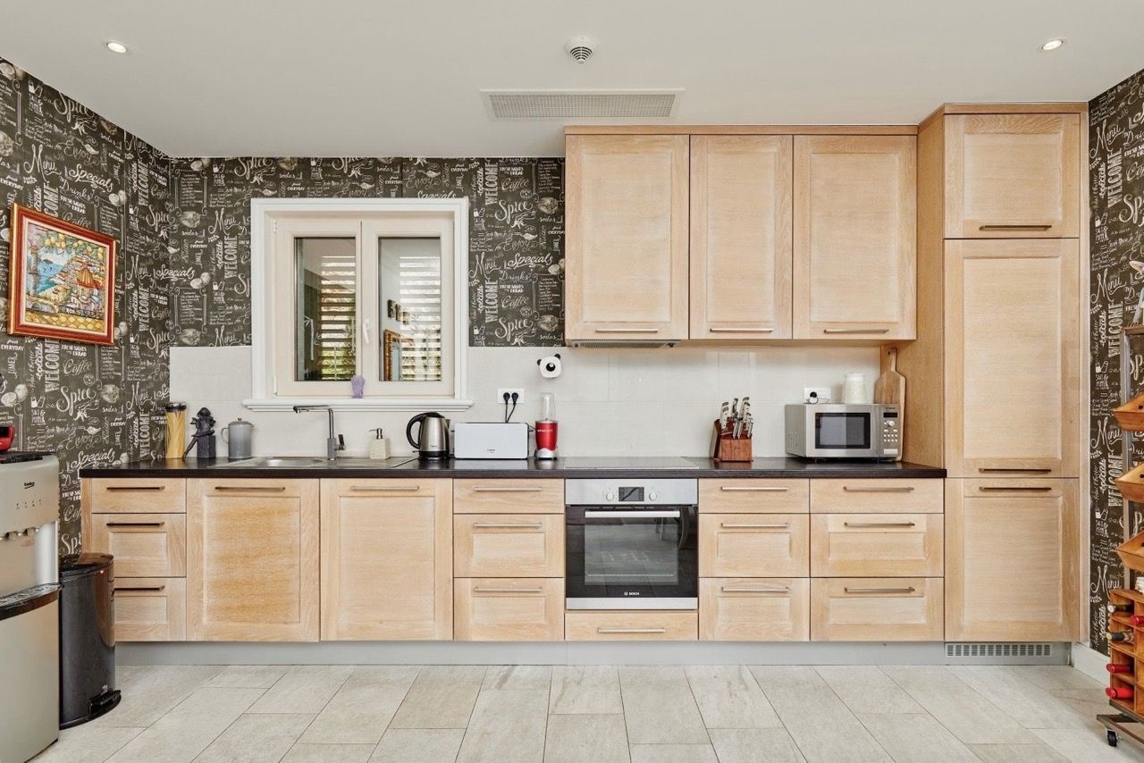 Cuisine moderne avec façades en bois dans l’appartement Luštica Bay, Radovići, Monténégro : électroménager intégré et décoration.
