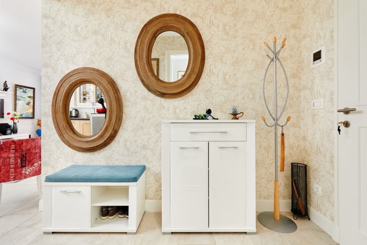 Entrée de l’appartement à Luštica Bay, Radovići, Monténégro : meubles blancs, miroirs ovales et porte-manteau.