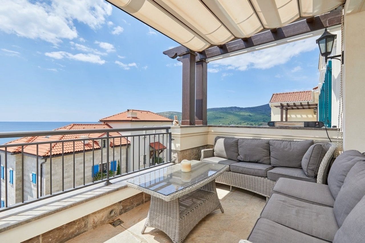 Terrasse avec mobilier en osier et vue sur la mer dans l’appartement de Luštica Bay, Radovići, Monténégro.