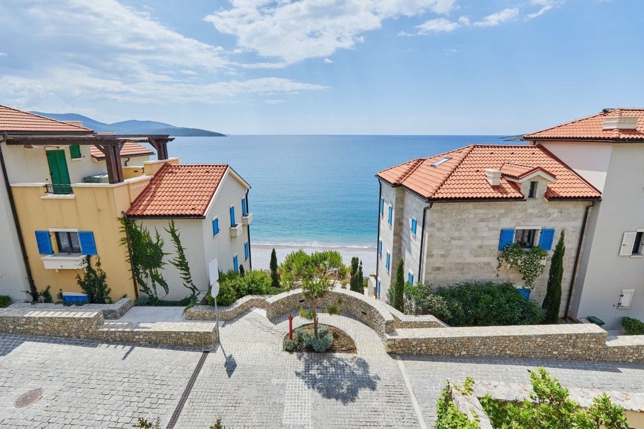 Vue sur la mer et la plage depuis le complexe de luxe Lustica Bay, Radovici, Monténégro : villas en pierre et allées pavées.