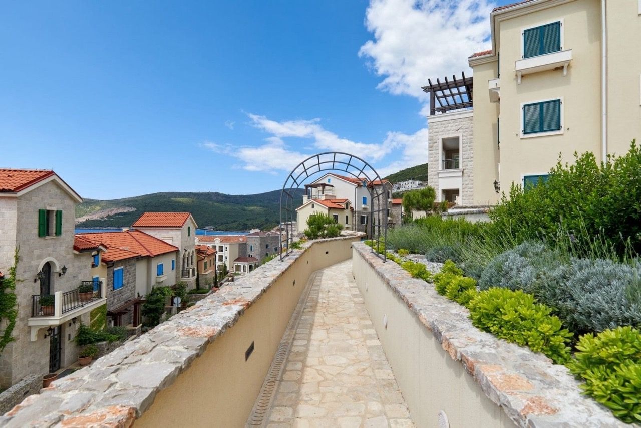 Vue sur le complexe résidentiel Lustica Bay à Radovići, Monténégro : allées en pierre, aménagement paysager et villas méditerranéennes.