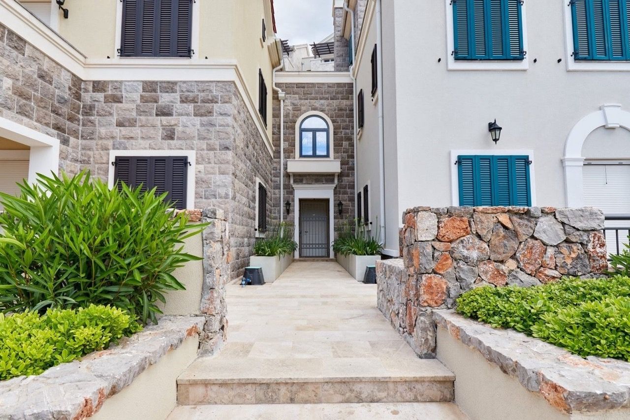Entrée d’un appartement de luxe à Luštica Bay, Radovići, Monténégro : façade en pierre, terrasse et aménagement paysager.