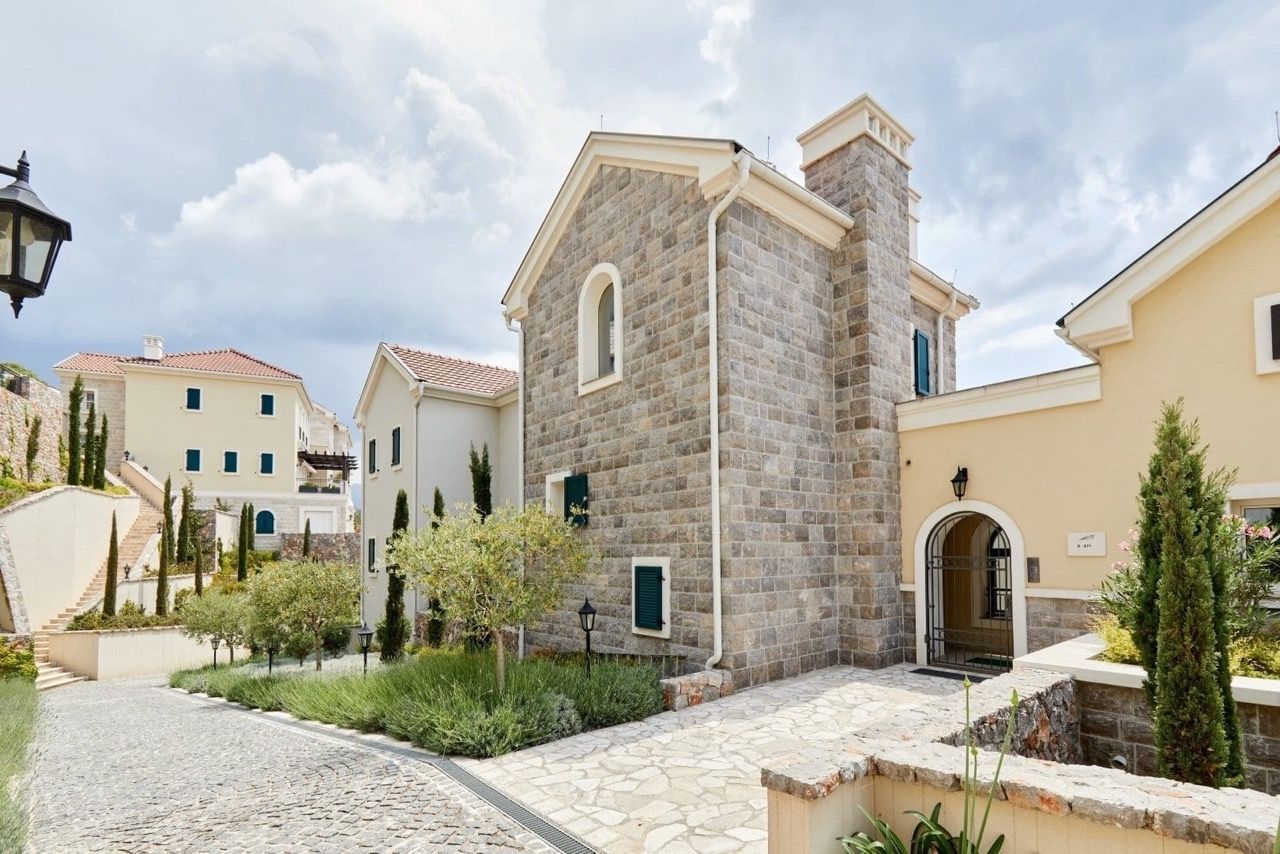 Façade d’une villa en pierre de style méditerranéen à Luštica Bay, Radovići, Monténégro, avec terrain aménagé.