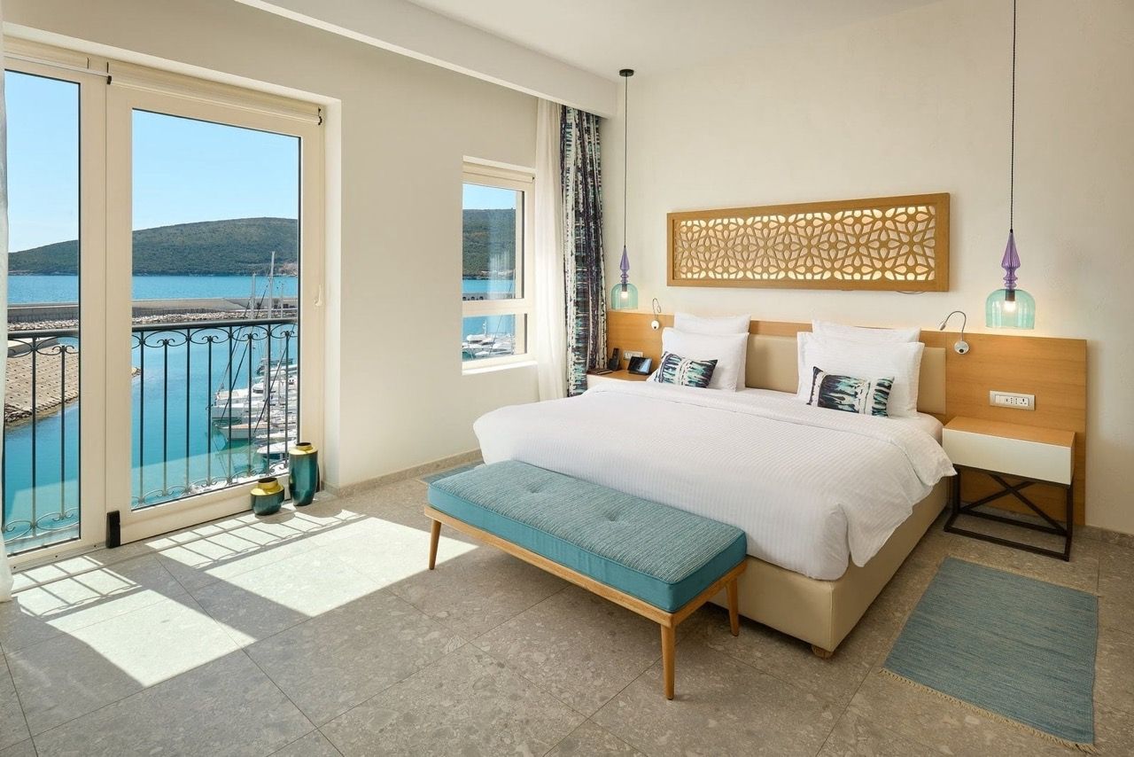 Chambre avec vue sur la marina à Luštica Bay, Radovići, Monténégro : lit double, décoration élégante et balcon en bord de mer.