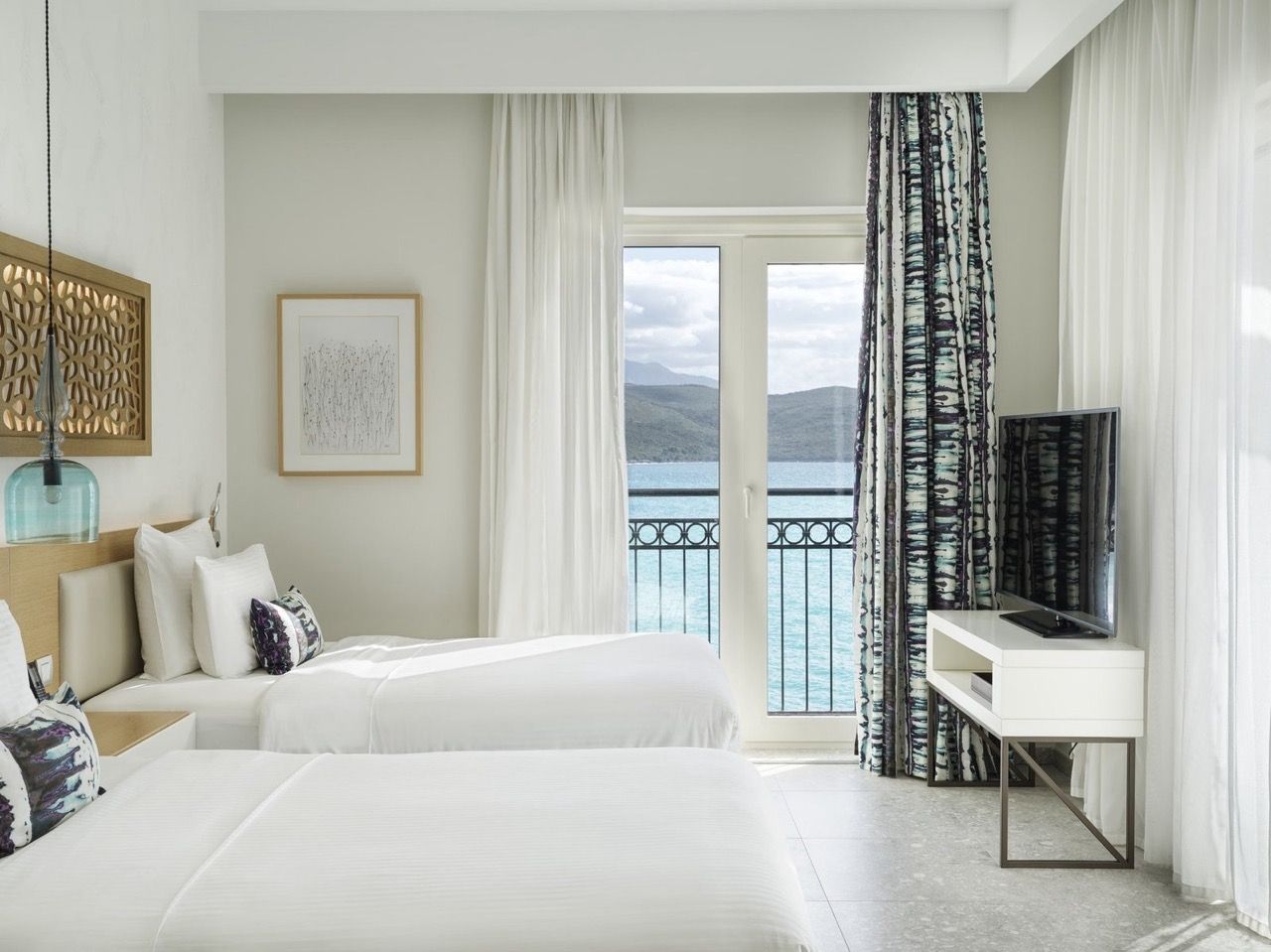Chambre dans les appartements Lustica Bay, Radovici, Monténégro : deux lits, mobilier moderne et vue sur la mer depuis le balcon.