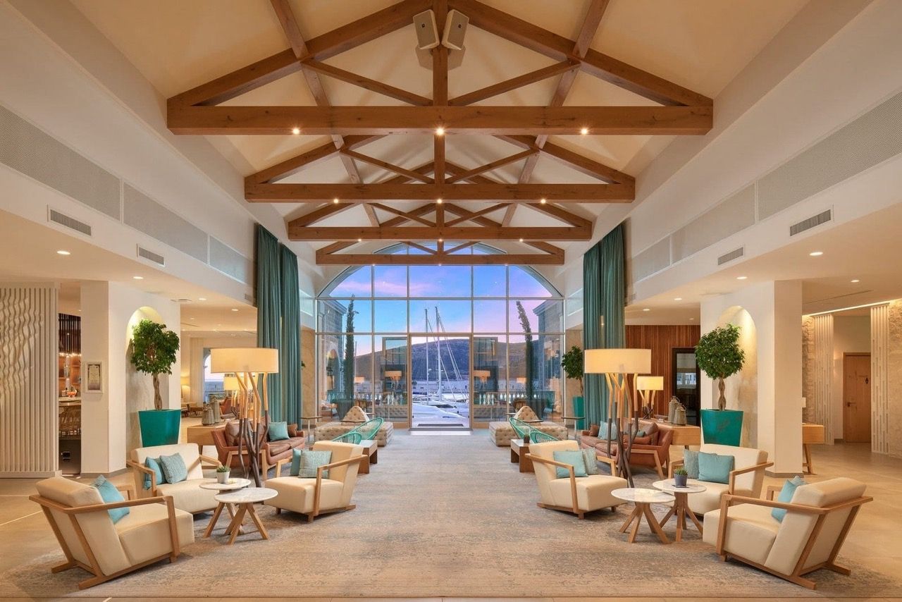 Intérieur du salon avec vue panoramique sur la marina à Luštica Bay, Radovići, Monténégro : poutres en bois et mobilier confortable.
