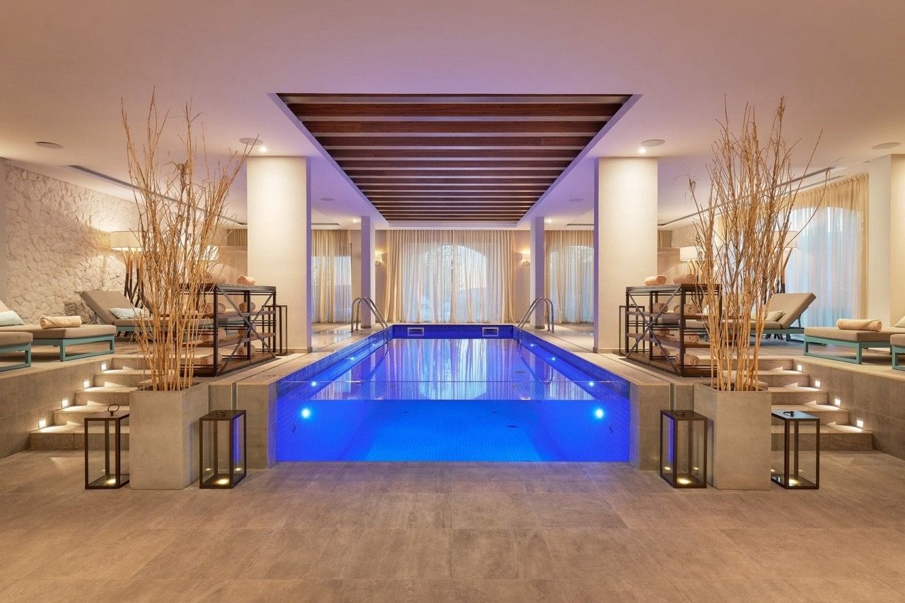 Piscine intérieure éclairée dans le spa du complexe Lustica Bay, Radovići, Monténégro : chaises longues et intérieur élégant.