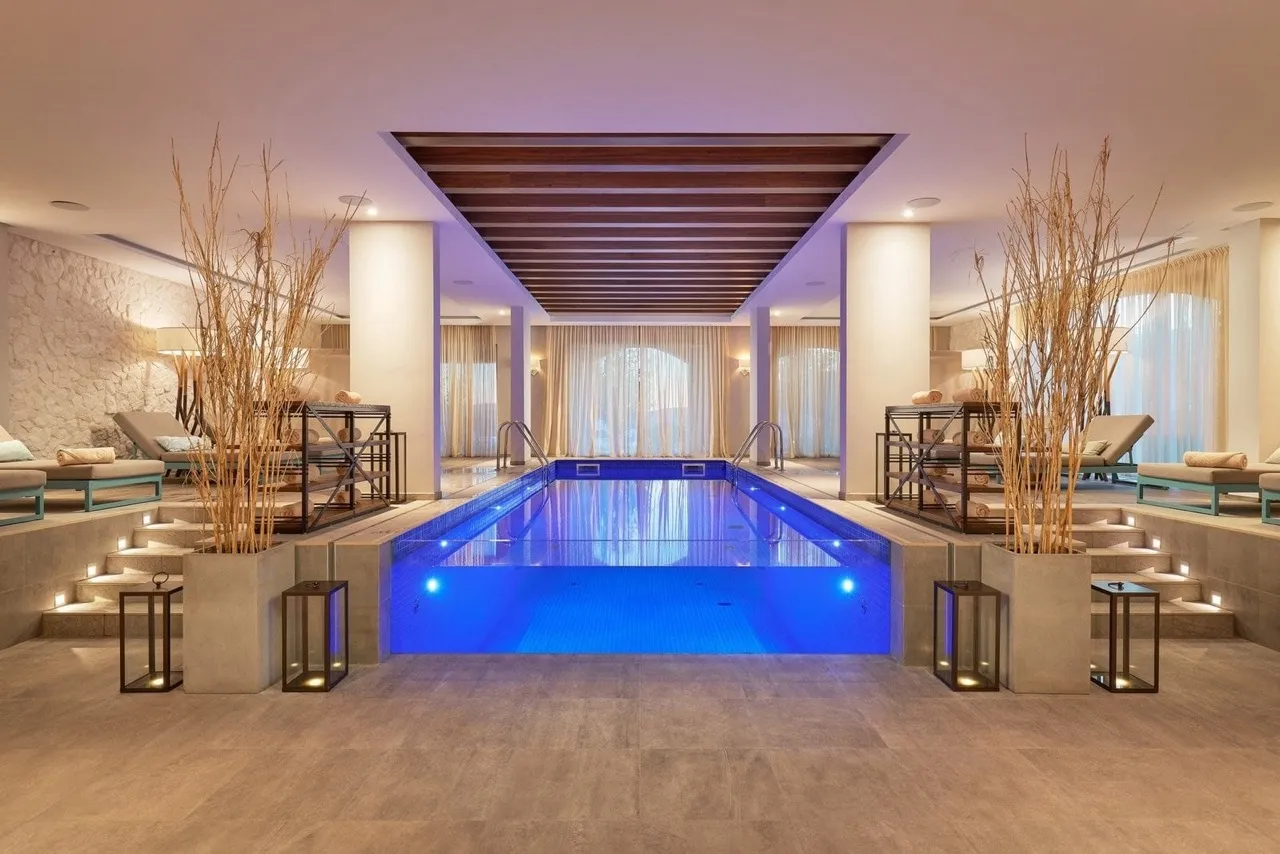 Крытый бассейн с подсветкой в спа-центре комплекса Lustica Bay, Радовичи, Черногория: шезлонги и стильный интерьер.