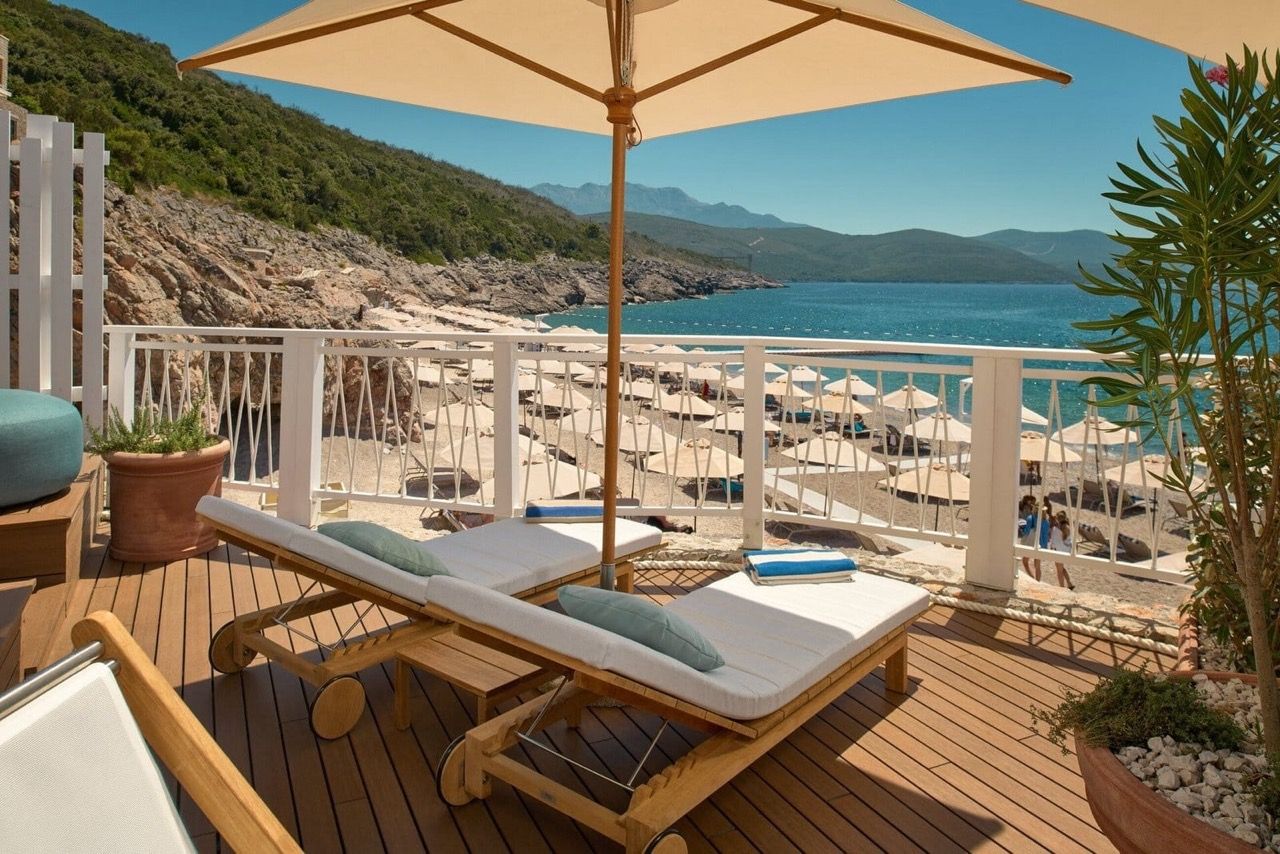 Terrasse avec chaises longues et vue sur la plage à Luštica Bay, Radovići, Monténégro : terrasse en bois et paysage marin.